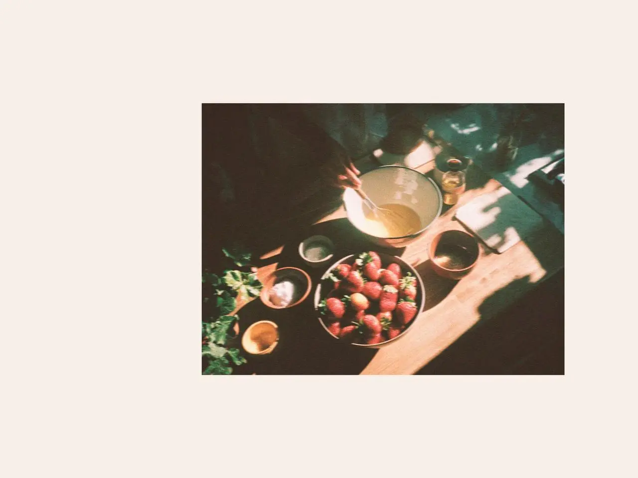 Fresh strawberries and cream being prepared in a bowl on a wooden table, creating a simple sweet easter dessert scene inspired by strawberry fools and warm sunset times for March.