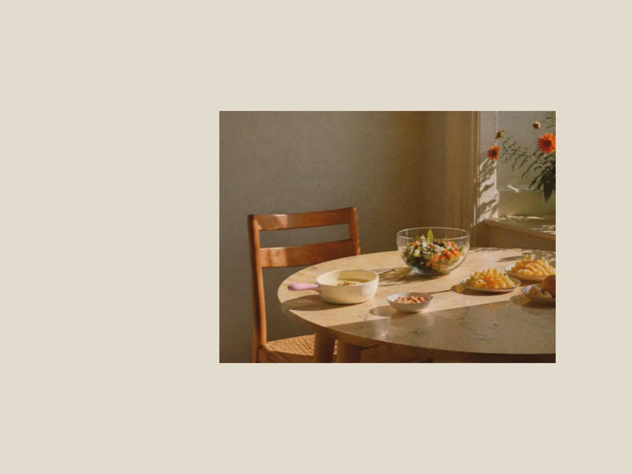 Round dining table with a large salad bowl, salad plates, and picnic dinnerware, styled with simple picnic accessories and designer tableware for a light family picnic and fruit salad sweet setting.