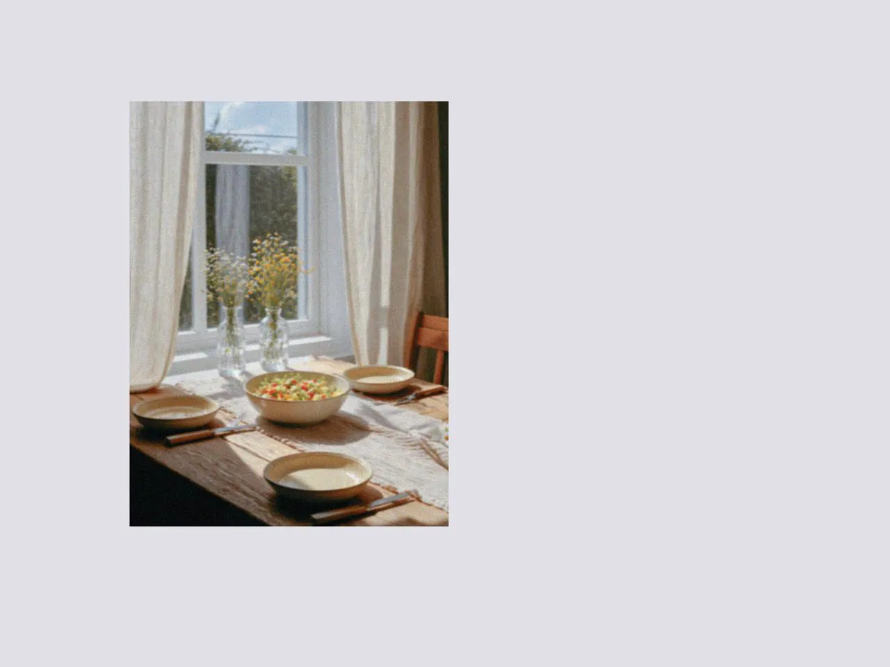 Sunlit dining table with a large salad bowl, matching salad plates, and picnic dinnerware, styled with simple picnic accessories and designer tableware for a fresh fruit salad sweet meal by the window.