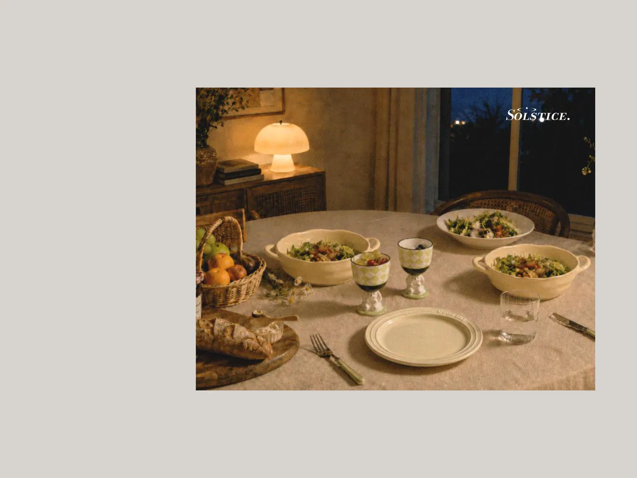 Evening dining table with picnic dinnerware, ceramic plates set, large salad bowl, salad plates, and ice cream cups, styled with designer tableware for a warm and relaxed shared meal indoors.