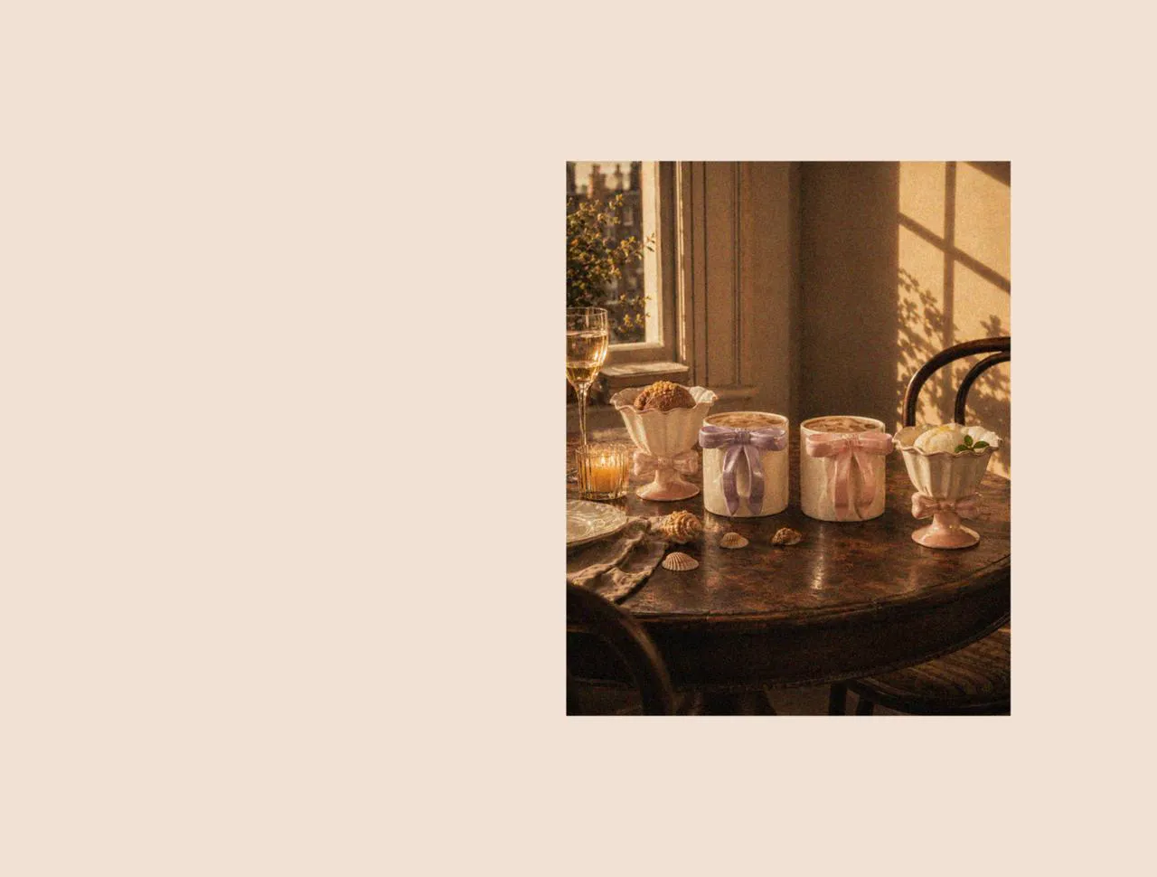 A coastal-inspired table styled with ceramic coffee mugs, a ceramic mug set, and elegant ice cream cups beside scattered beach shells, creating a calm and inviting atmosphere in London during summer.