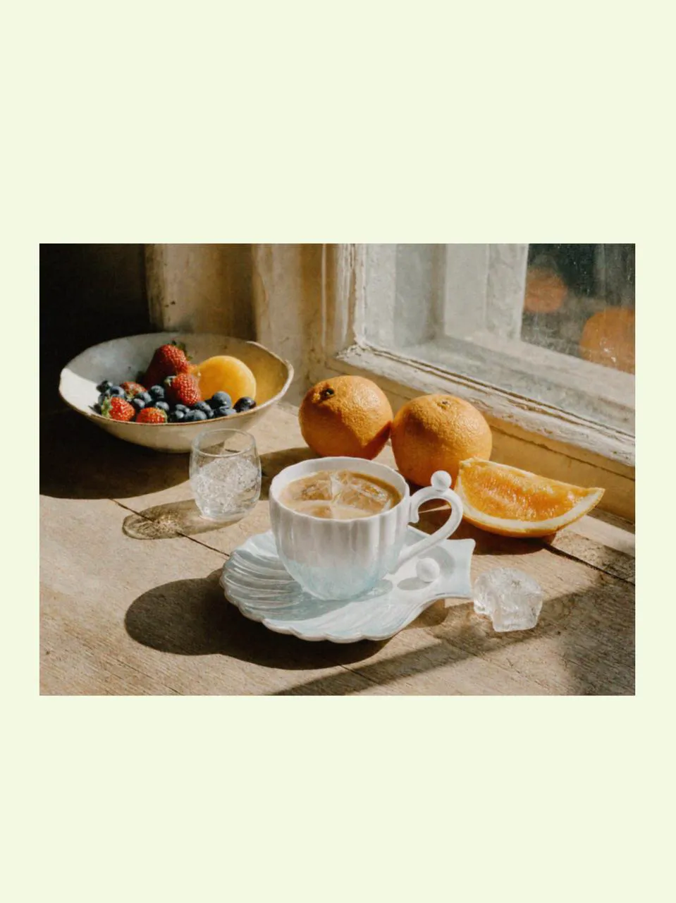 Designer coffee mug and mugs for latte beside fruit and summery things, featuring soft beach shell inspiration and a cooling summer atmosphere by the window.